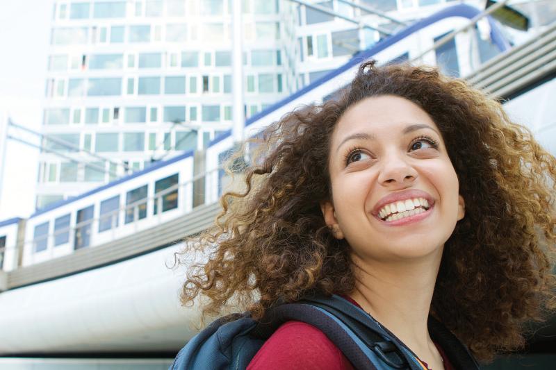 woman backpack smiling outside train station