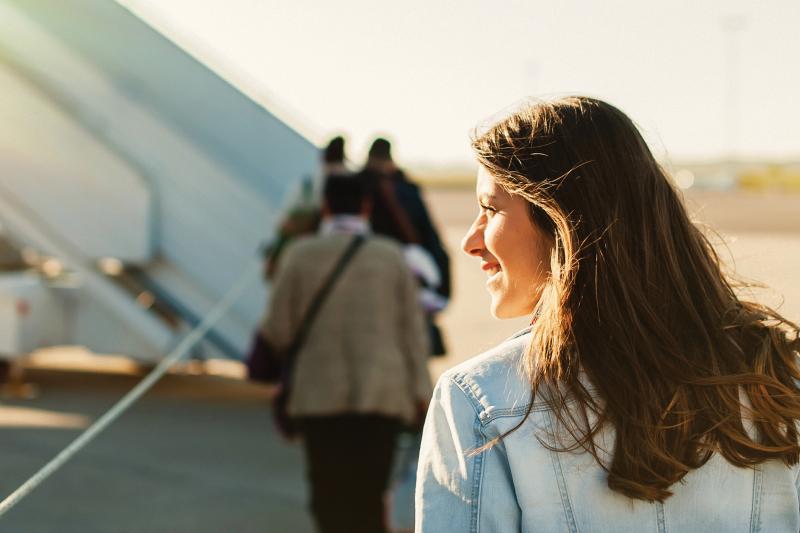 Woman boarding airplane with sunlight in the background