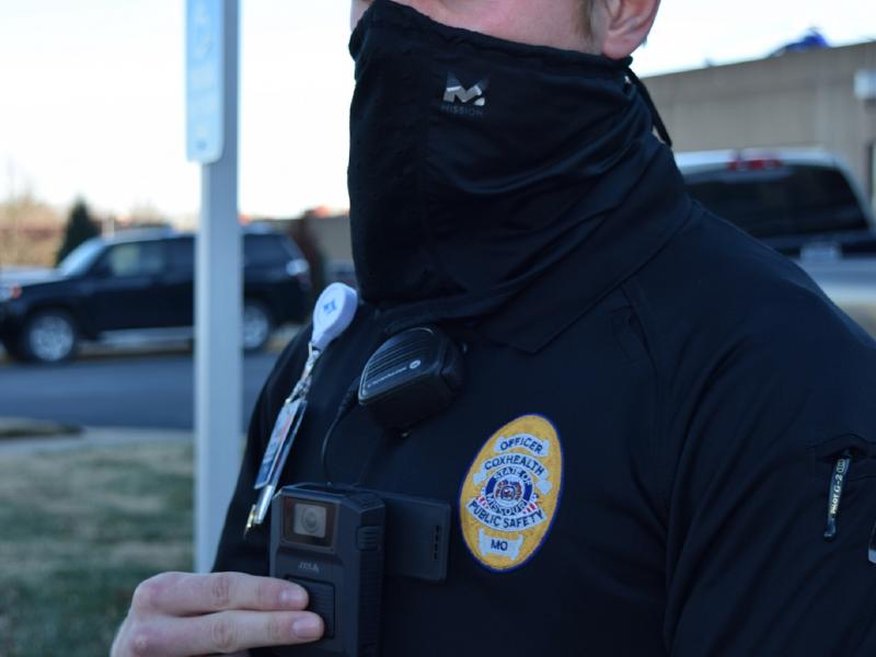 Security officer depresses button to activate body worn camera