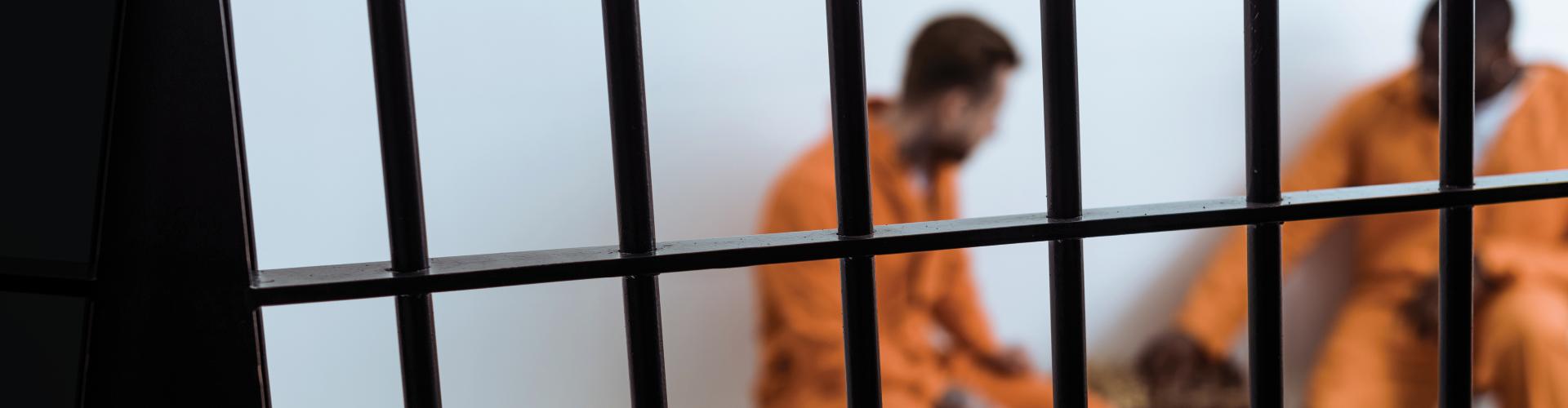 Inmates in orange clothing behind bars