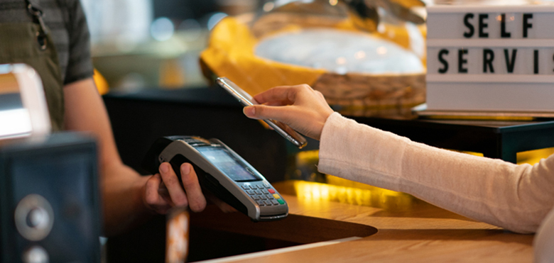 Neue Normalität im Einzelhandel: Kunde, der dank kontaktloser Zahlung mit einem Mobiltelefon bezahlt.
