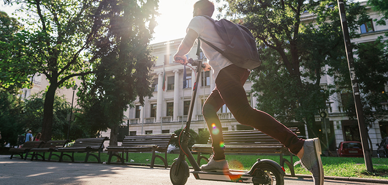 Mobilität in einer intelligenten Stadt: ein Mann fährt auf einem E-Roller durch den Park