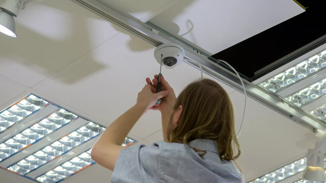 AXIS T91A33 Lighting Track Mount, an installer screwing the lighting track