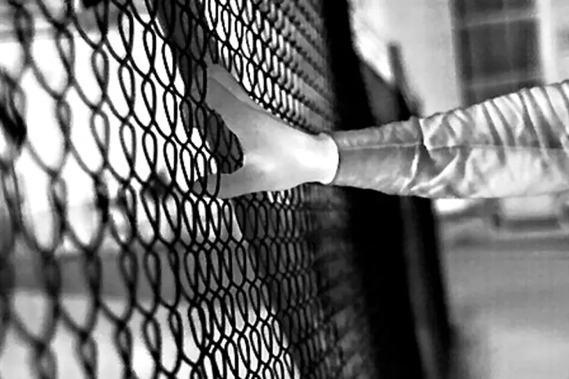 Black and white footage of hand grabbing fence in the dark.