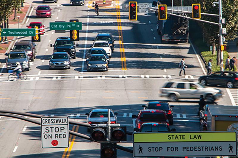 Street intersection with red signals and signs for crosswalk.