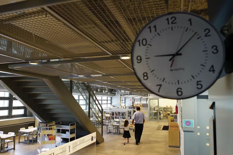 School from inside, clock in front and man and child in background.