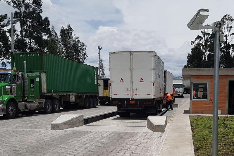 A few white trucks and one green, one man about to get into one of them.