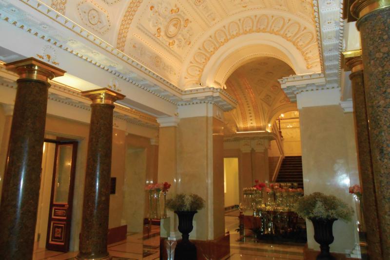Hotel interior entrance, yellow poles and ceiling with flowers in vases.