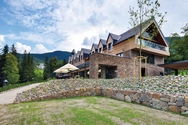 Brown wooden modern building on countryside viewed from its left angle.