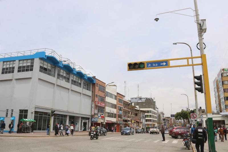 City street in Peru with cars, people and yellow pole for traffic light.