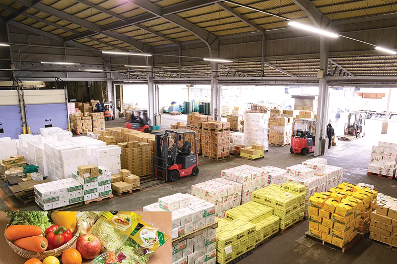 Warehouse with trucks and magnification of vegetables in left corner.