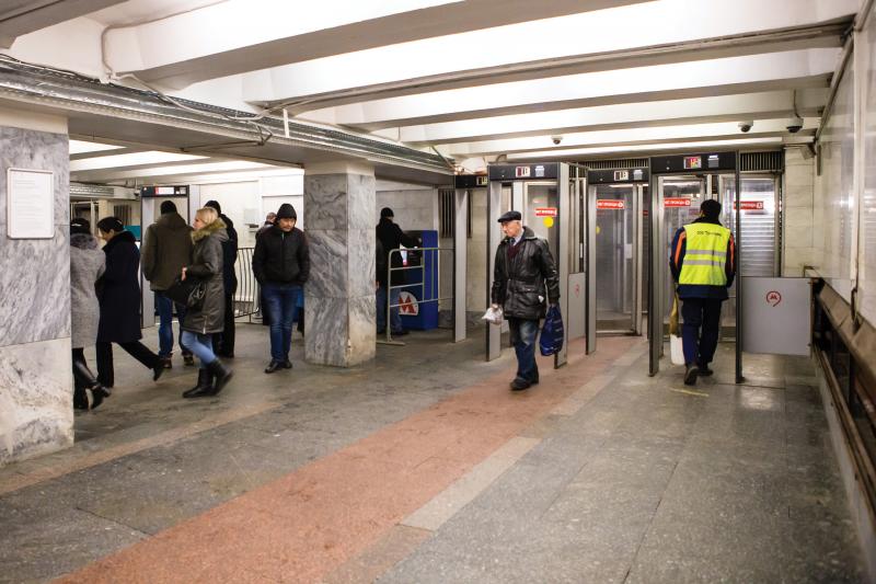 Underground subway station, people moving, one with yellow vest.