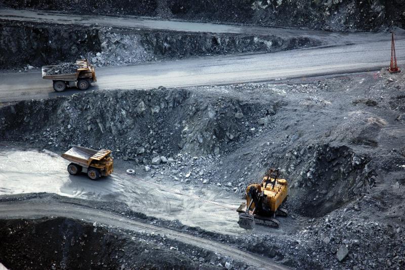 Dump trucks work in a open pit mining