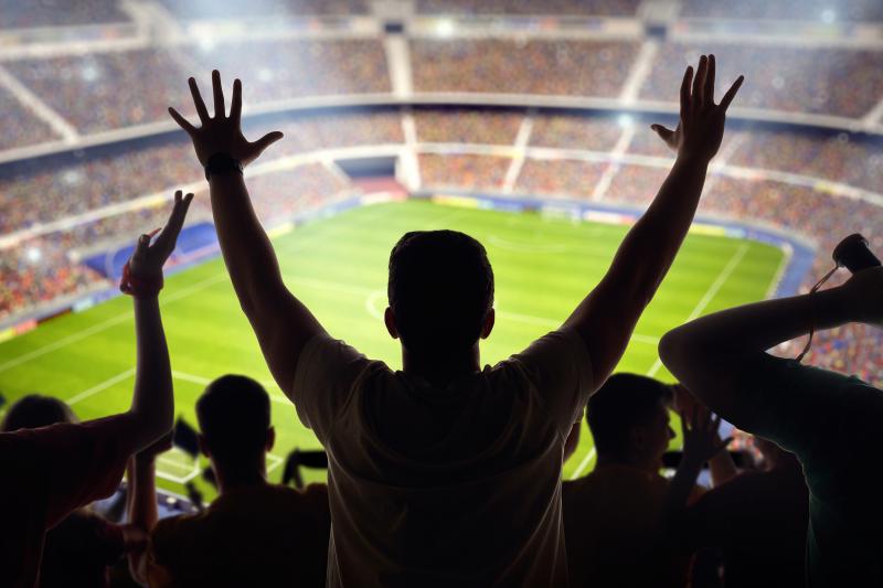 Silhouettes of spectators looking out over a soccer stadium 