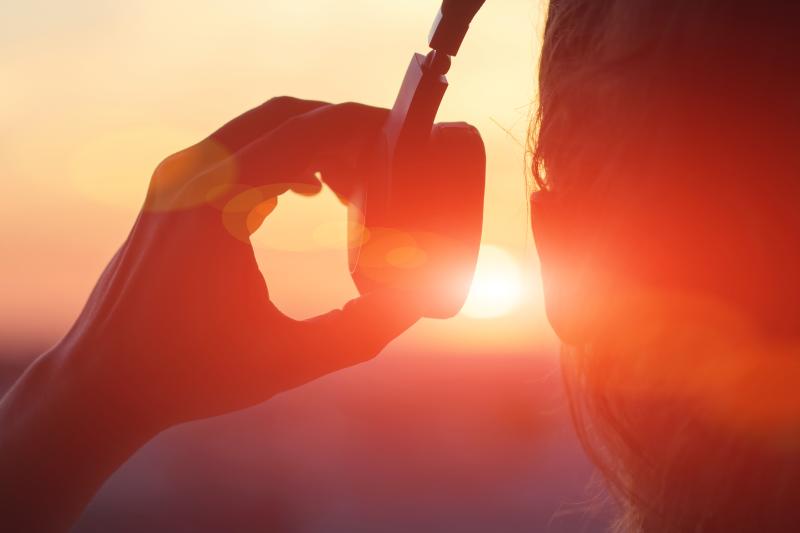 silhouette of a woman with headphone in front of a sunset