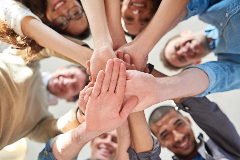 Big group of people smiling while handstacking above the camera.