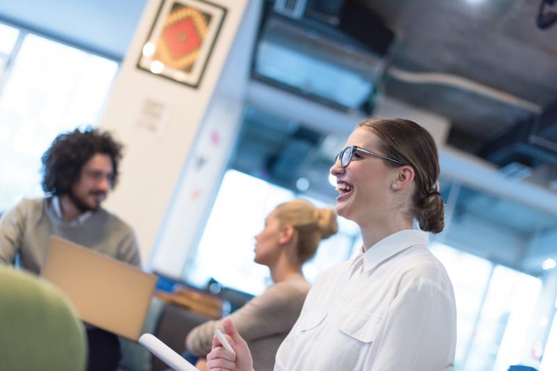 Woman smiling in front of other people while holding a chalk.