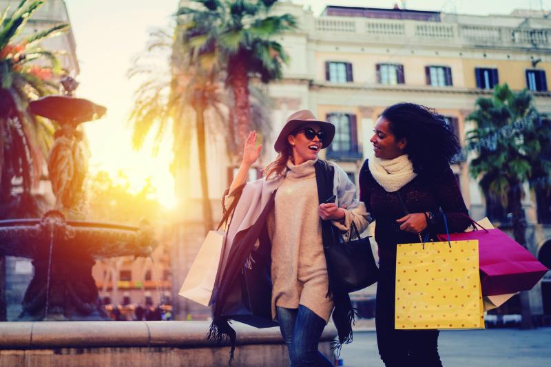 two women shopping outdoors, fountain in the background