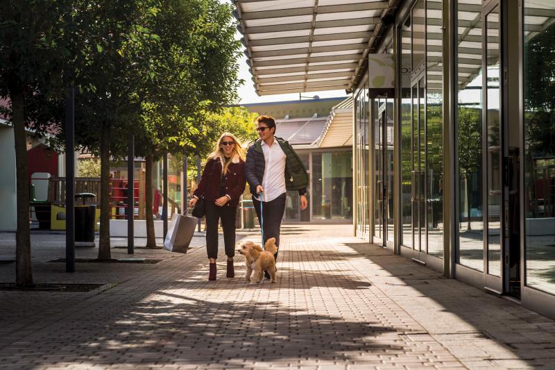 Man and woman walking dog outside shopping mall