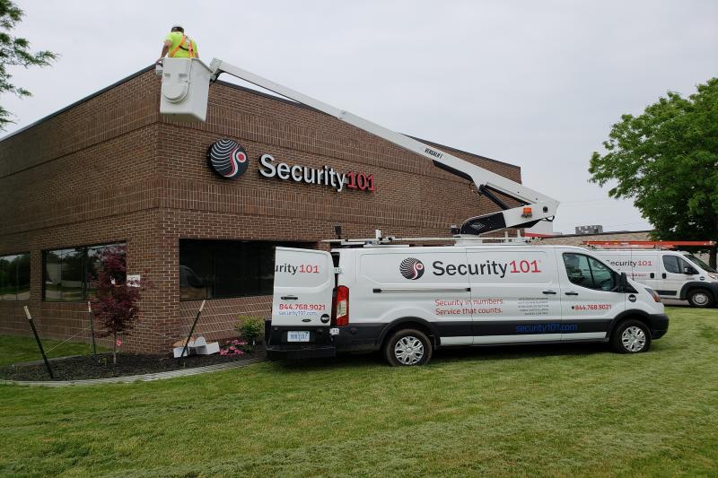 Security 101 personnel in bucket truck installing camera on building