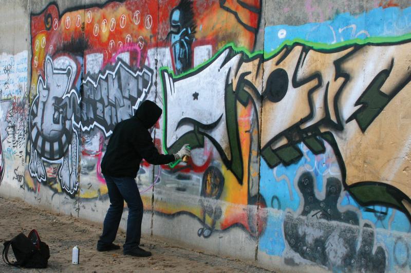 Graffiti man vandalize by spray printing a public wall
