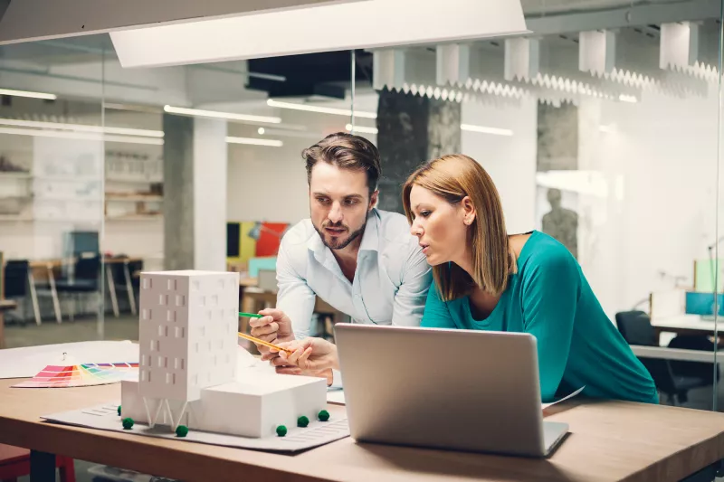 Man and woman discussing about an architectural building model