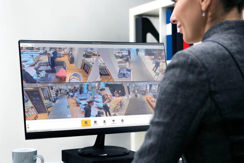 woman, sitting in front of a computer screen, using AXIS Camera Station