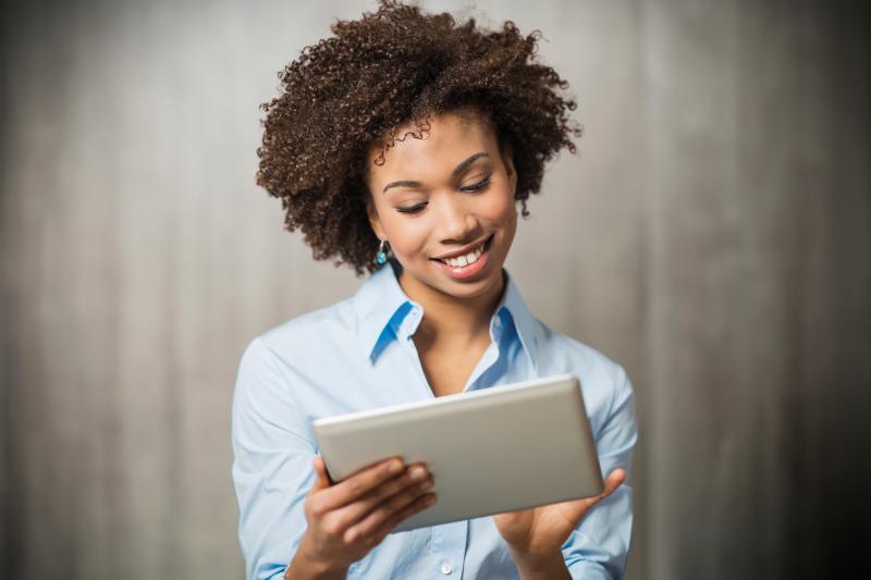Business woman, holding a tablet. Grey background. 