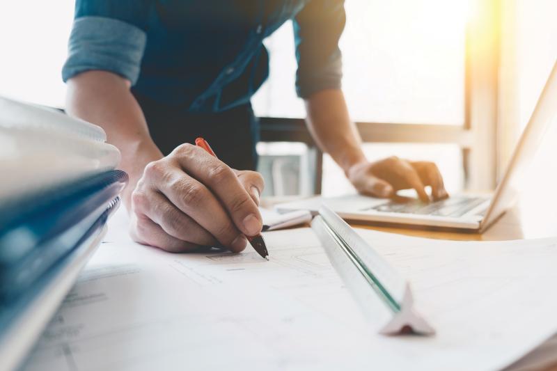 A hand holding a pen, making a technical drawing