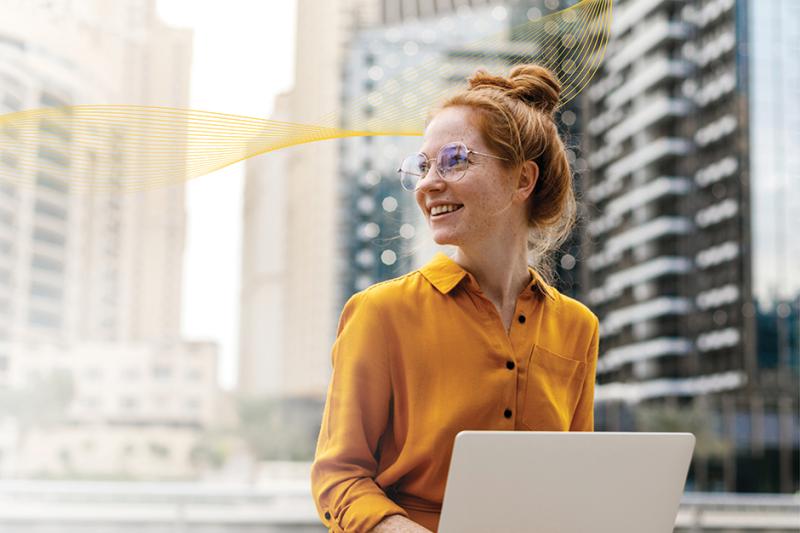 Person in orange sweater working on laptop