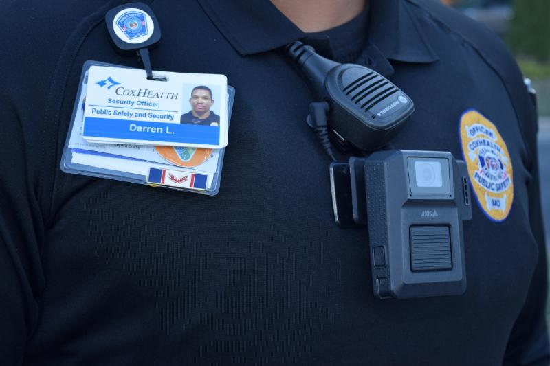 Close up of security officer's chest showing body worn camera, ID, and badge