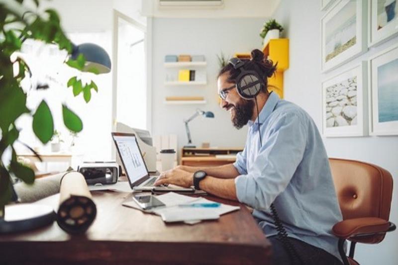 Bearded man in headphones looking at computer screen
