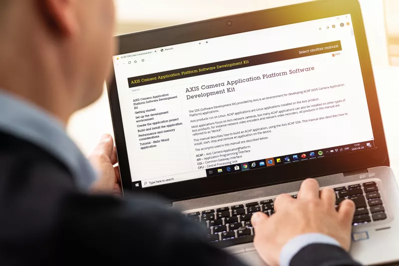 A man sitting by the laptop, looking over his shoulder