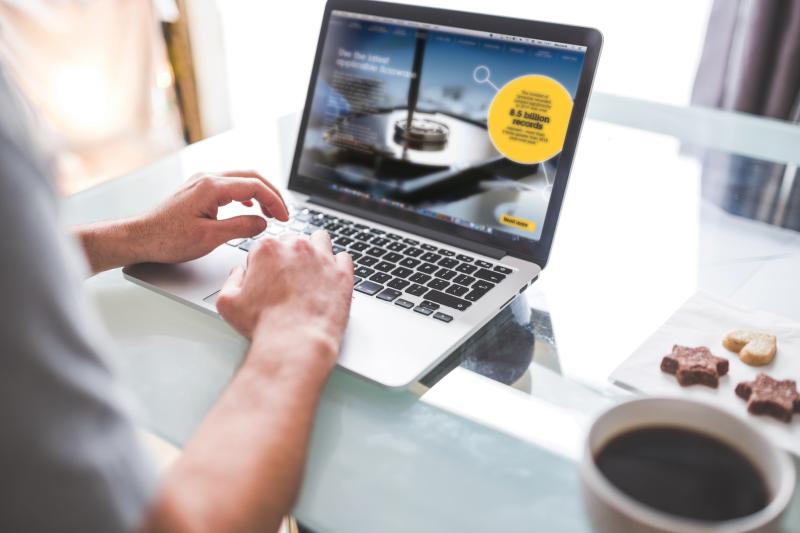 Hands on laptop, with a cup of coffee next to it.