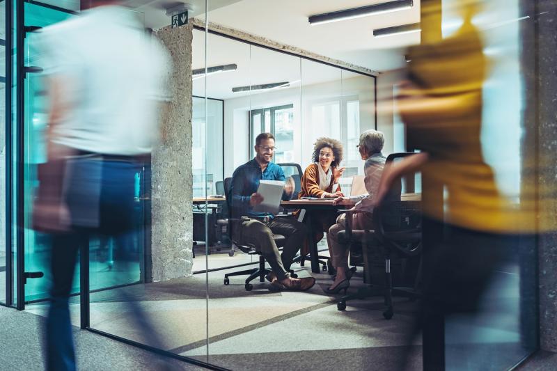 Three people, having a discussion in a meeting room at a office