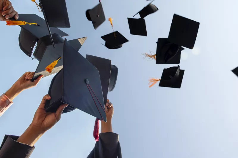 Graduation caps hands throwing sky