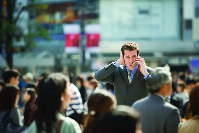 Business man on the phone in the city with lots of noice