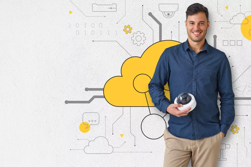 man standing holding a camera, behind a wall with yellow cloud illustration