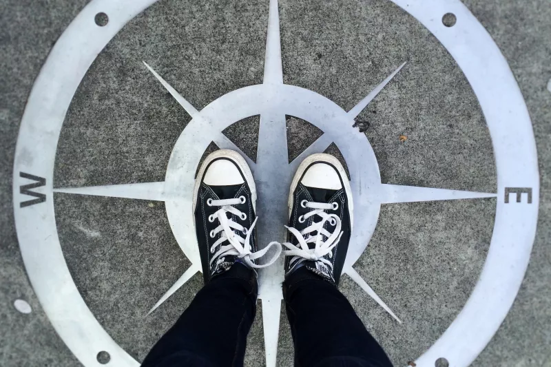 Two feet standing on the ground with a compass