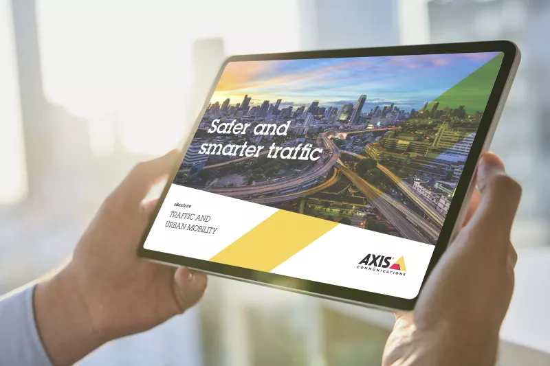 Person holding an ipad reading an ebrochure about how axis network devices create smarter and safer traffic and urban mobility