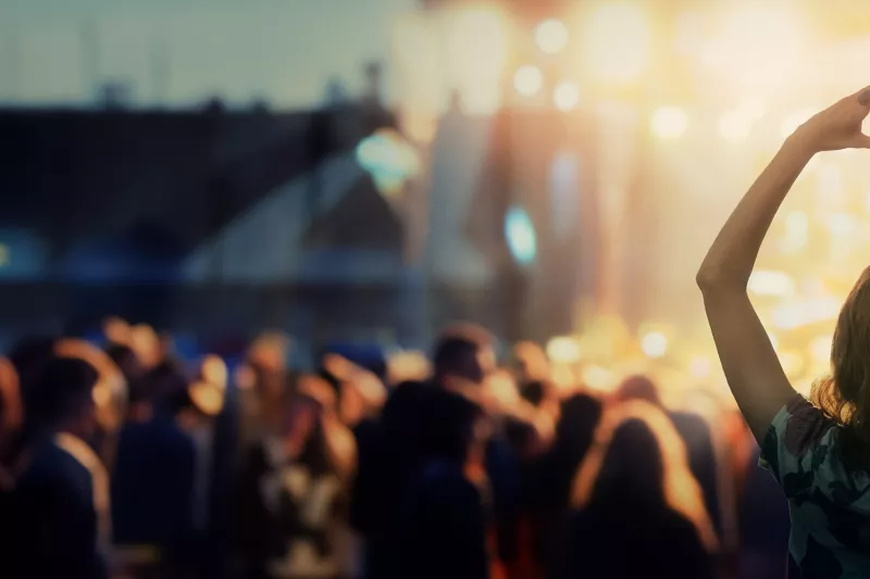Concert with people and a woman holding hands shaped like a heart.