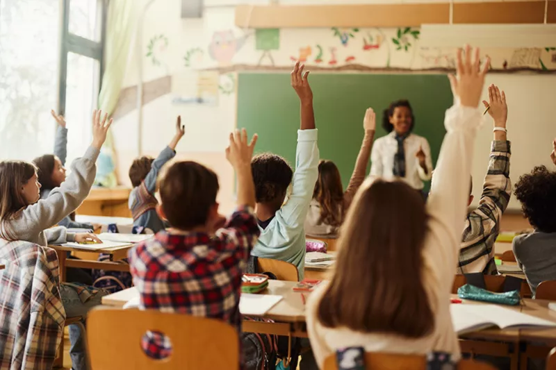 Children in class with hand raised