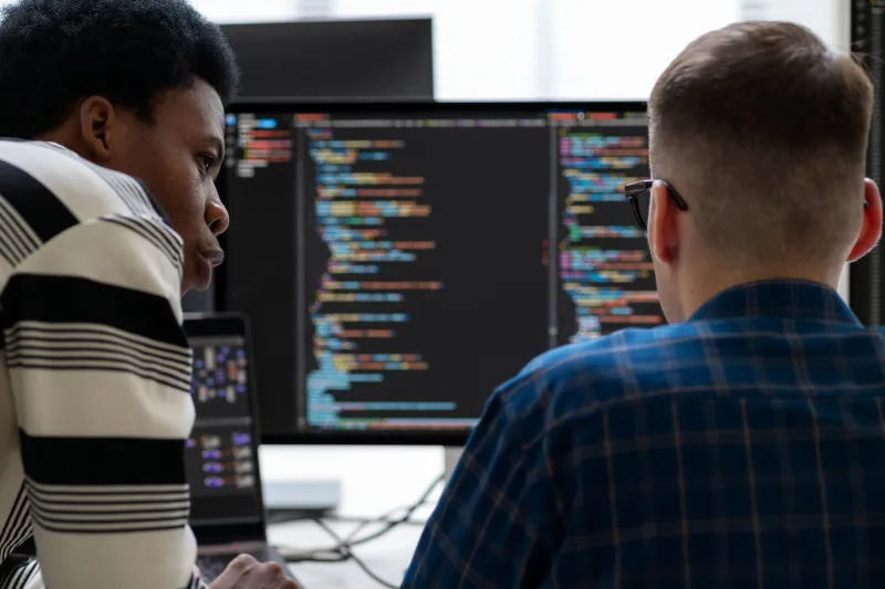 Two men looking at computer with code