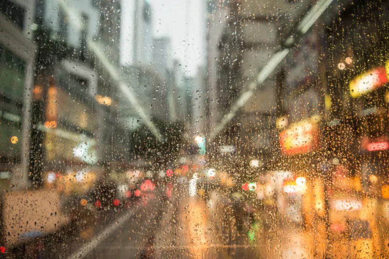 Blurred view of a city with lights due to rain on the window.
