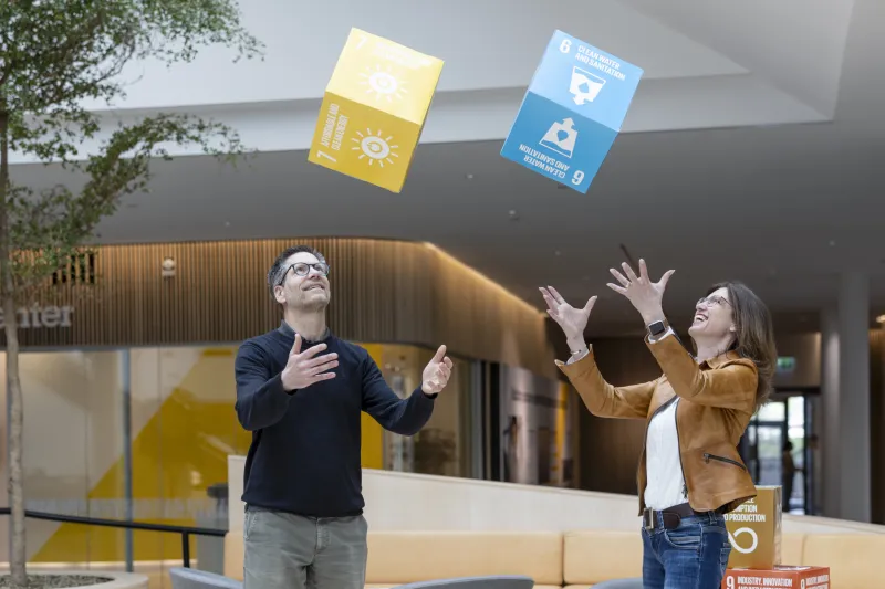 Carl Trotzig and Jeanette Skjelmose are seen throwing cubes with FN global goals written on them. 