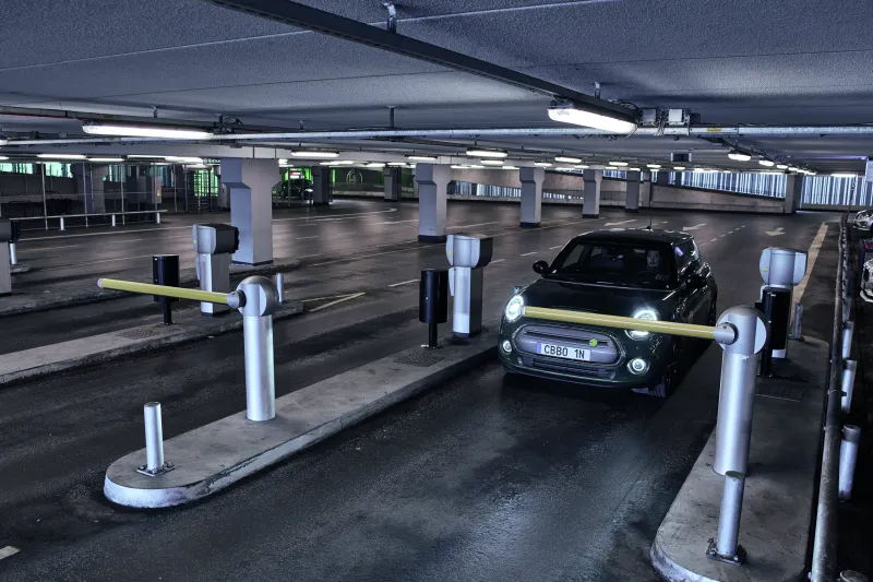 A black car exiting a dark parking garage.