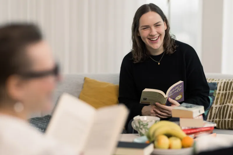 Victoria Vucic seen laughing and holding a book, while sitting in the Axis book club
