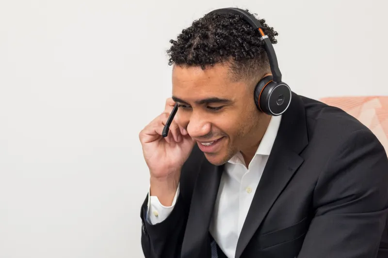 Axis employee Jon-Pablo wearing a headset and smiling while taking a business call.