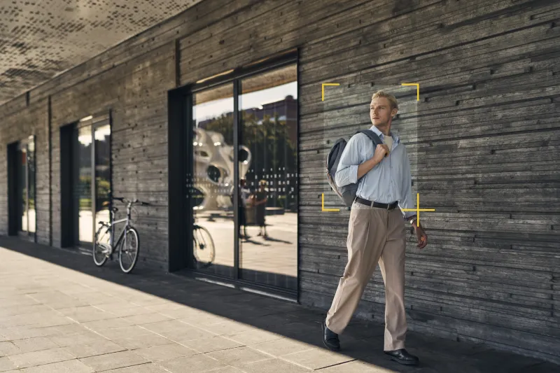 Man walking outside a big building with object detection frame around him.