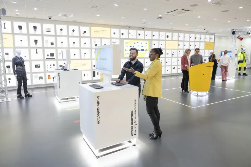 People exploring Axis products in an Experience Center. The wall is lined with Axis cameras and products.